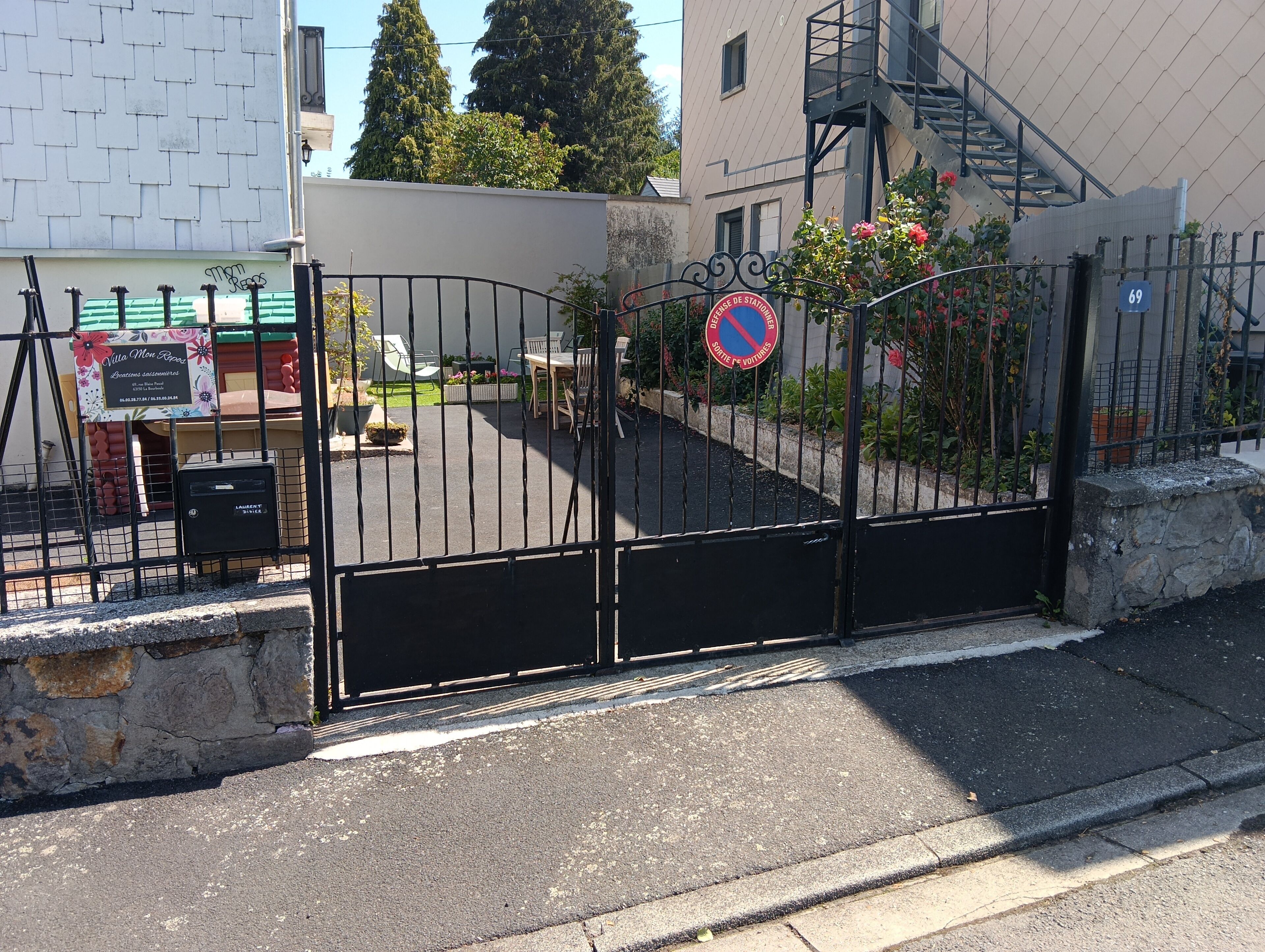 Ein begrenzter Eingangsbereich mit Durchfahrtskontrolle, einem Verbotsschild für das Parken, einem Briefkasten und einem Schild für Villa Mon Bar.