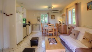 Un espacio habitable compacto con kitchenette, comedor y un sofá con almohadas que dicen 'HOME'.