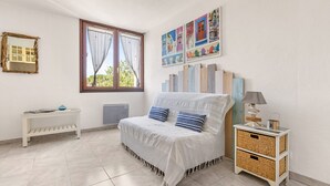 Un dormitorio con cama, mesita de noche, lámpara y una pared decorada con obras de arte.