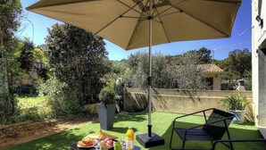 En terrasse med et bord dækket til et måltid, en stol og en stor parasol.
