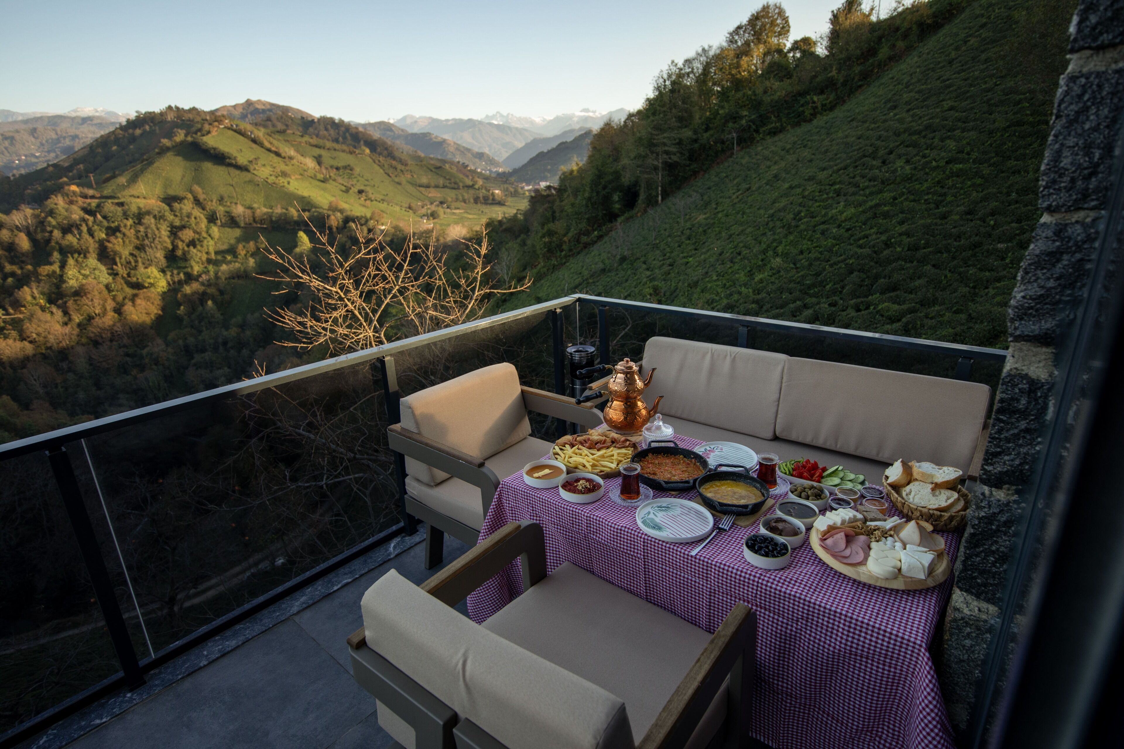A balcony with a table set for a meal, overlooking a mountainous landscape.
