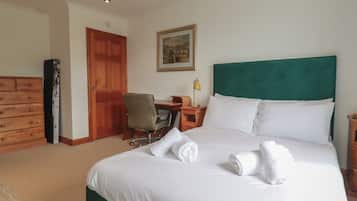 Quarto de hotel com cama, escrivaninha, cadeira, cômoda e porta.