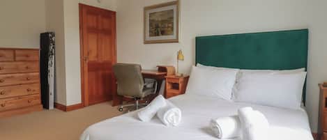 Een hotelkamer met een bed, een bureau, een stoel, een dressoir en een deur.