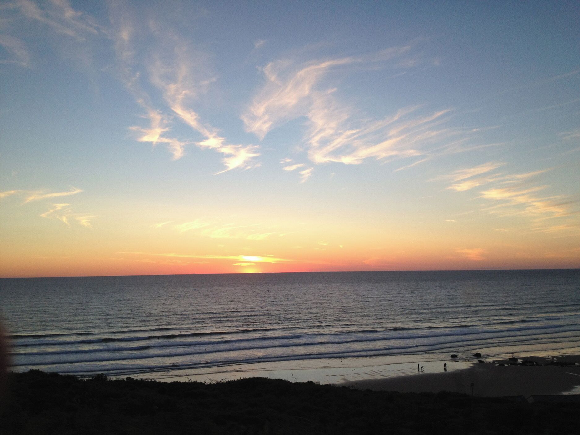A sunset over the ocean with a clear sky.