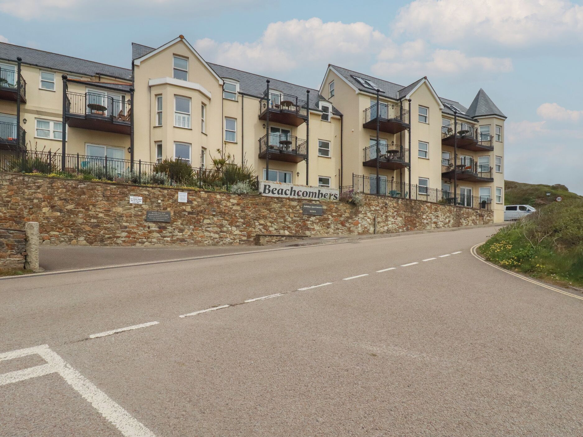 Ein mehrstöckiges Hotel namens Beachcombers mit einer Steinfassade, Balkonen und einer klaren Straße davor.