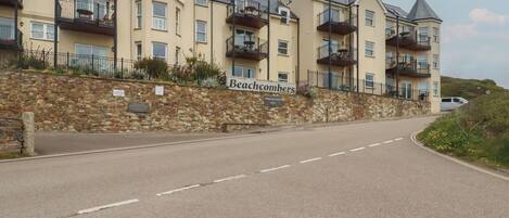 Ein mehrstöckiges Hotel namens Beachcombers mit einer Steinfassade, Balkonen und einer klaren Straße davor.
