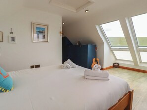 A bedroom with a bed, a guitar, and a window. - Lowenna (Newquay)