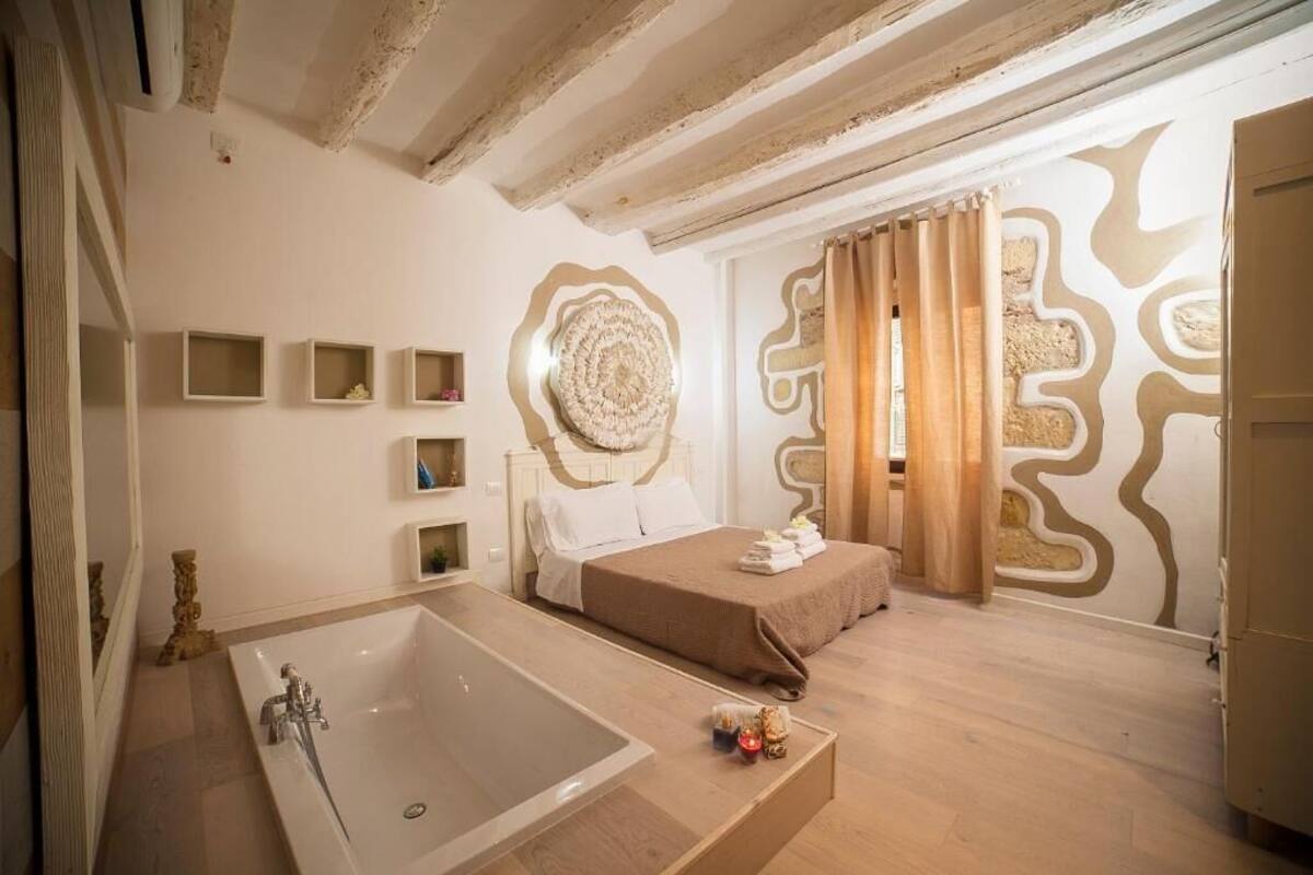 Un dormitorio con una bañera grande, una cama con manta marrón y un adorno de pared.