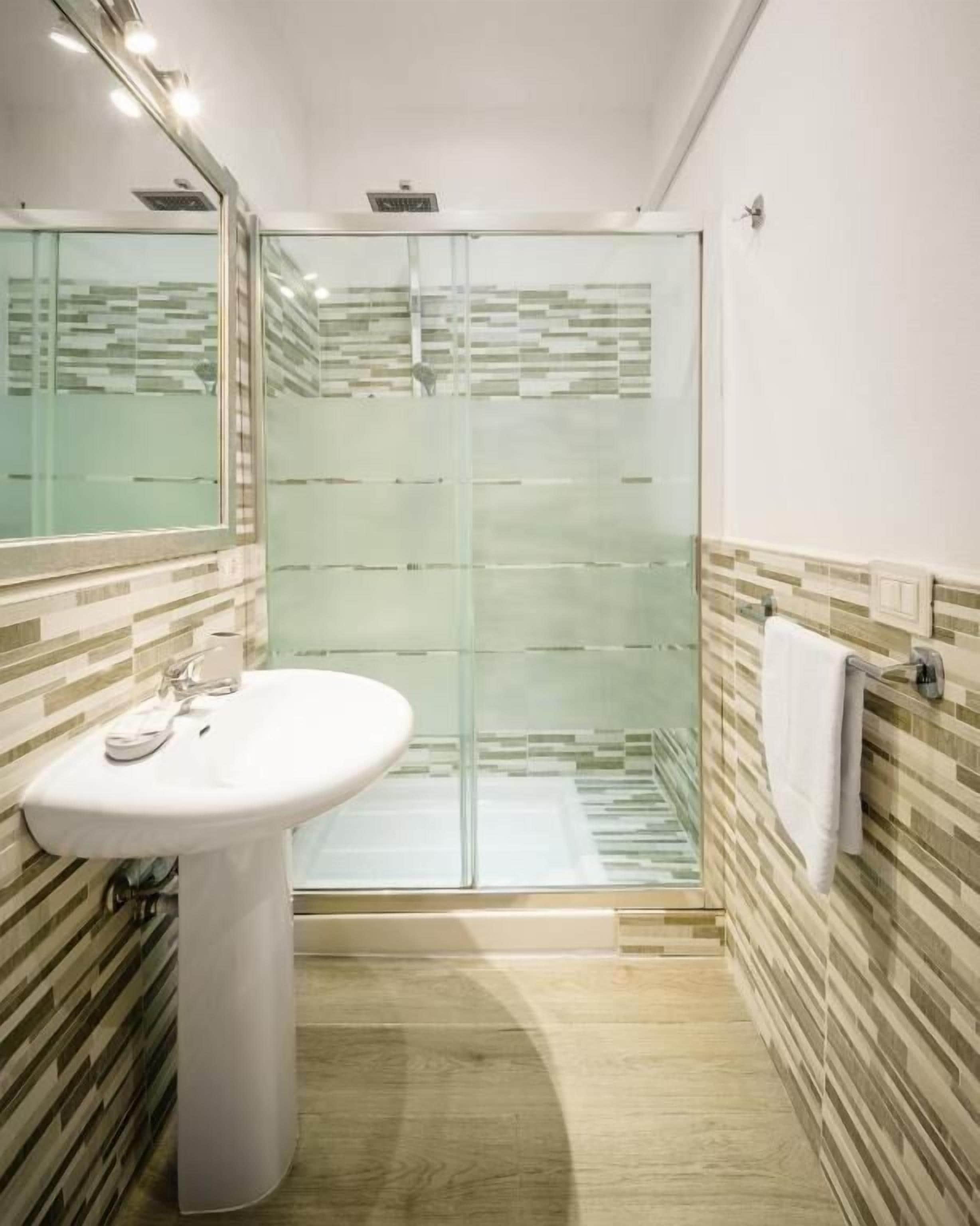 Een badkamer met een douchecabine van glas, een wit wastafelmeubel en een handdoekhouder.