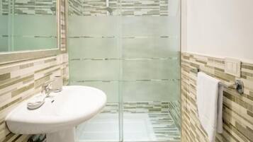 Een badkamer met een douchecabine van glas, een wit wastafelmeubel en een handdoekhouder.