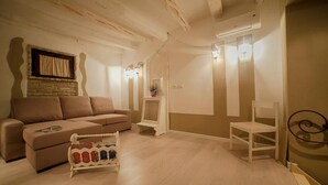 A living room with a sofa, a small table, a chair, and a decorative item on the floor. - Oisife Apartments (Cagliari)