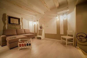 Un soggiorno con un divano, un tavolino, una sedia e un oggetto decorativo sul pavimento.