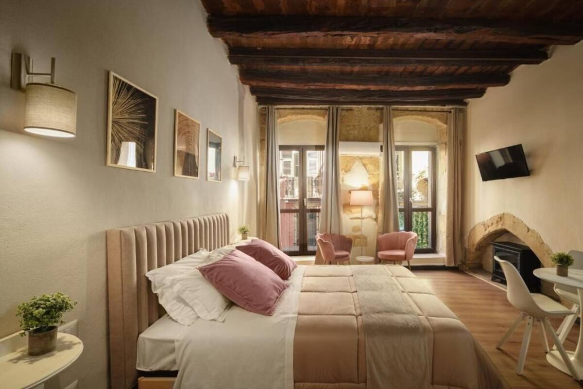 Un dormitorio con cama, mesitas de noche, chimenea y televisión.