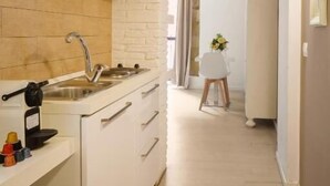A narrow kitchen with a sink, cabinets, and a countertop. There is a doorway leading to another room. - Oisife Apartments (Cagliari)