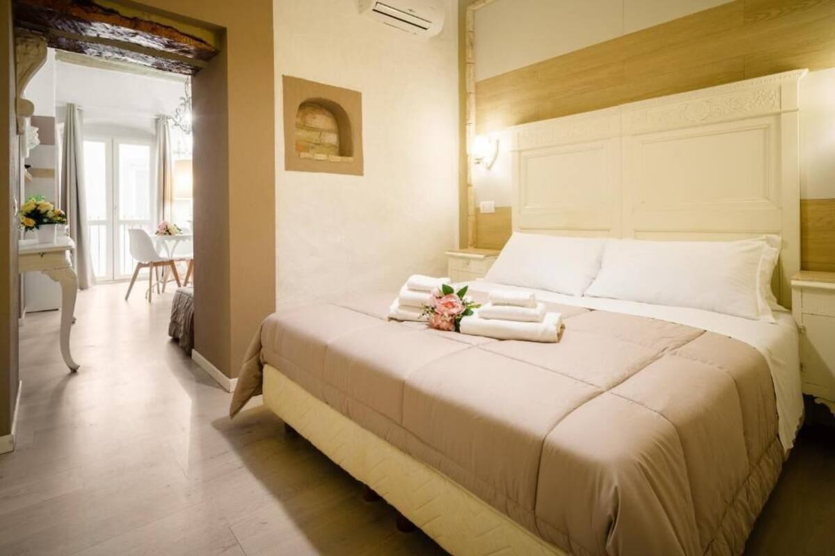Habitación de hotel con una cama grande, un escritorio con silla y vistas a un balcón.