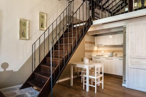 A staircase leading to a loft bedroom with a kitchen area below.