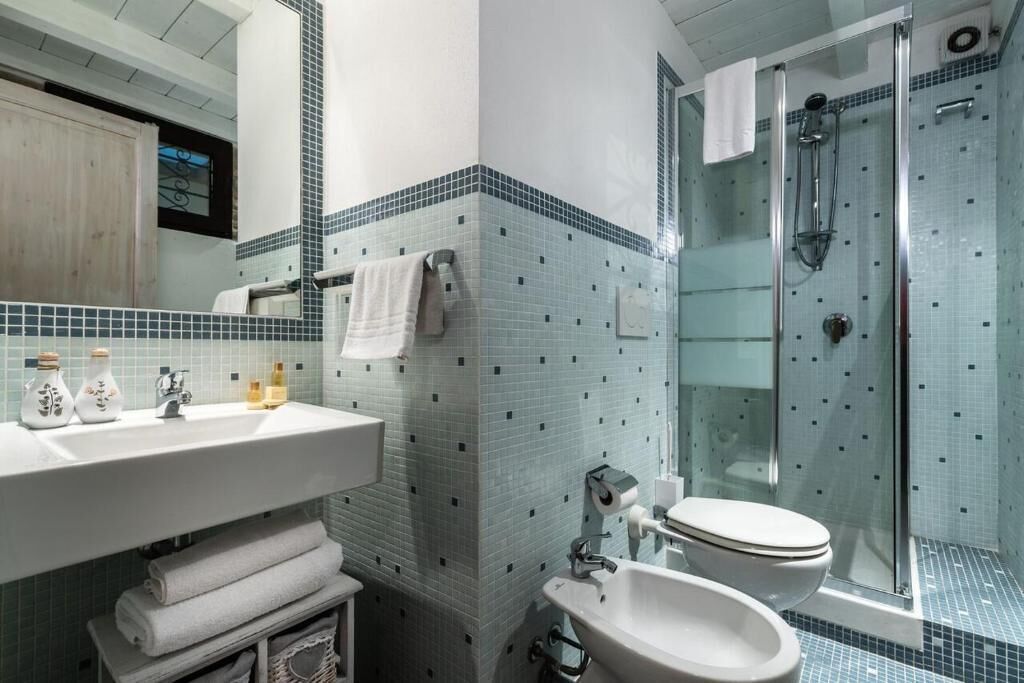 A bathroom with a glass shower enclosure, a sink, and a toilet.