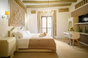 A bedroom with a bed, a desk, a chair, a TV, and a chandelier. - Oisife Apartments (Cagliari)