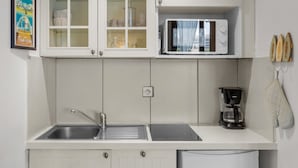 Una cocina con un lavaplatos, microondas y cafetera.