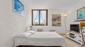 Un dormitorio con cama, televisión, lámpara y obras de arte en las paredes.