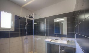Ein modernes Badezimmer mit Duschkabine aus Glas, Waschbecken und Spiegel.