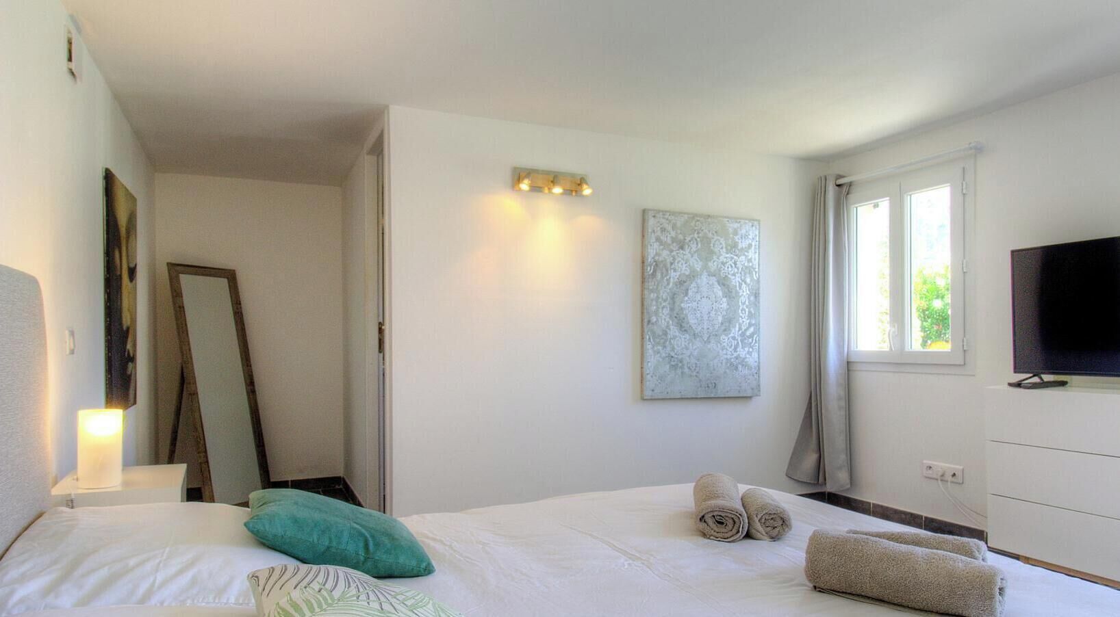 Una camera da letto con un letto, una televisione, un quadro e una finestra.