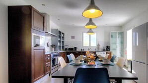 Une cuisine moderne avec des meubles en bois, une table à manger pour quatre personnes et un réfrigérateur.