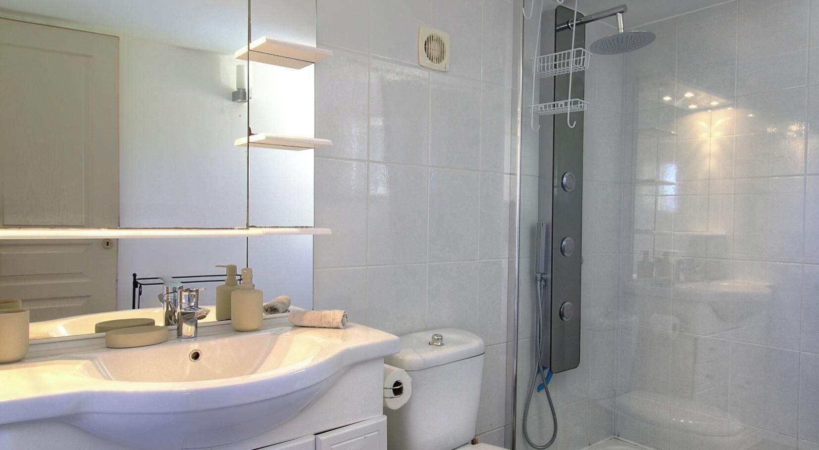 A modern bathroom with a large sink, toilet, and shower.