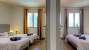Une chambre d’hôtel avec deux lits, une fenêtre, des rideaux et une lampe de chevet.