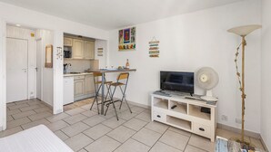 Ein gemütlicher Wohnbereich mit Küchenzeile, Essplatz, Fernseher und Stehlampe.