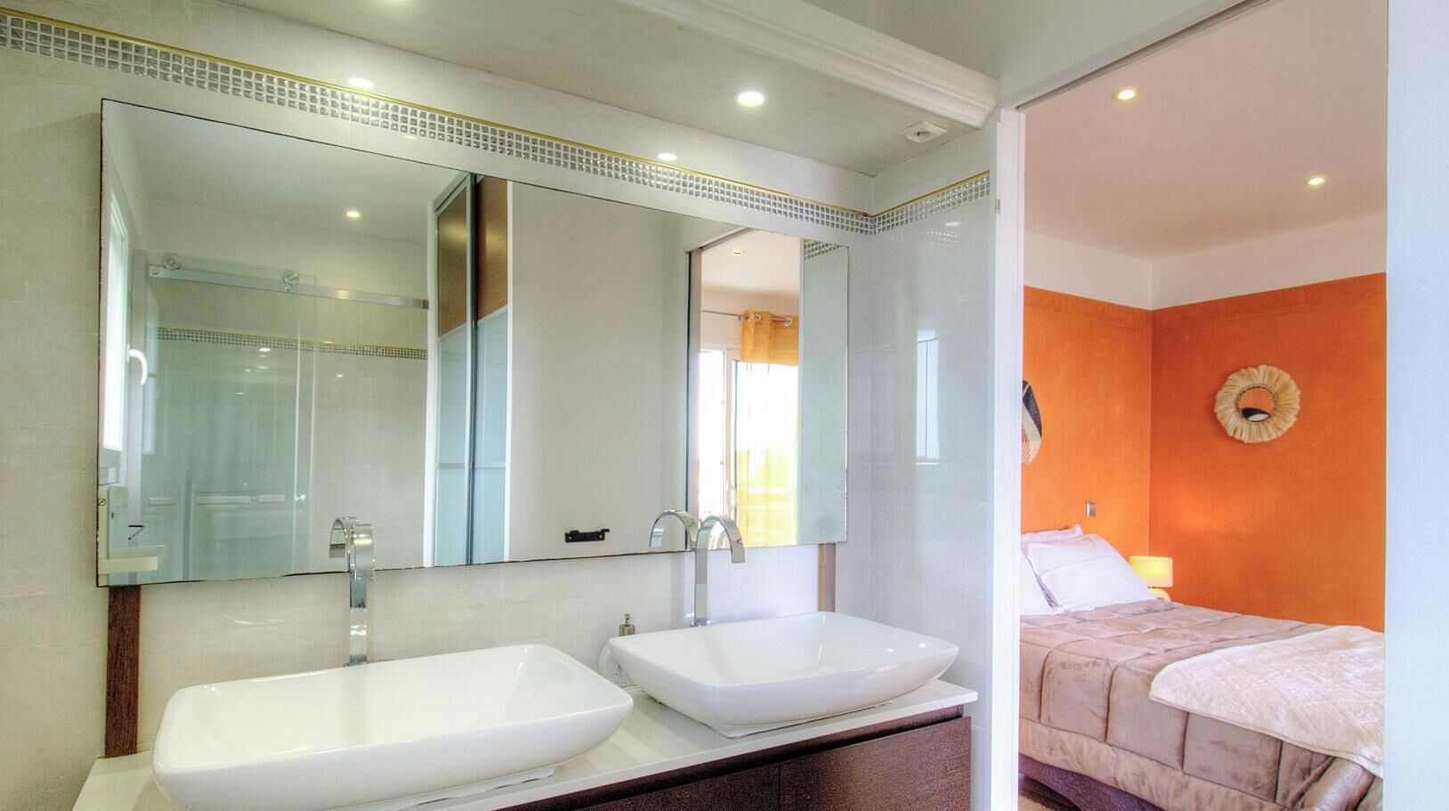 A bathroom with two sinks, a large mirror, and a shower.
