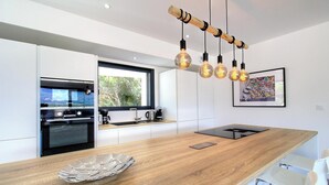 A modern kitchen with a wooden countertop, built-in oven, and pendant lighting. - Casa Di l'Alba - CALVI (CALVI)