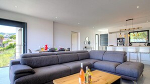A modern living room with a sectional sofa, a wooden coffee table, and a kitchen in the background. - Casa Di l'Alba - CALVI (CALVI)