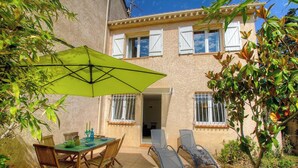 Eine Terrasse mit Tisch, Stühlen und Sonnenschirm.
