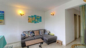 Ein Wohnzimmer mit grauem Sofa, einem kleinen Tisch und Wandbildern.