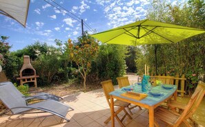 Eine Terrassensitzgruppe mit Tisch, Stühlen und einem grünen Sonnenschirm.