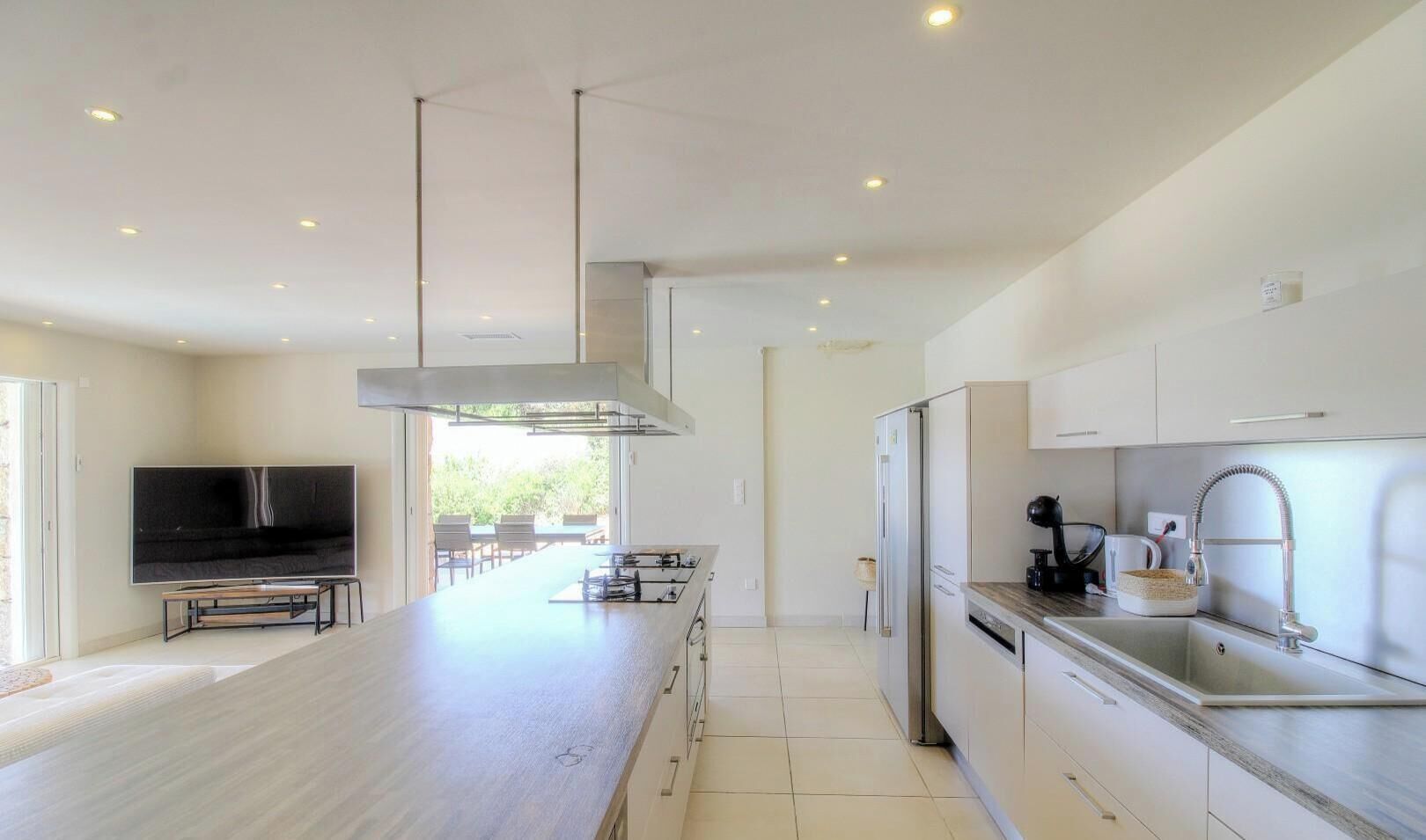 A modern kitchen with a central island, stainless steel appliances, and a dining area with a view.