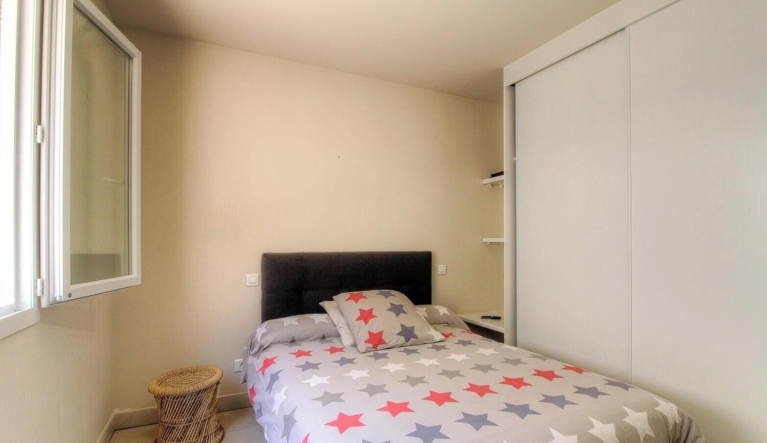 A small bedroom with a bed, a window, and a wardrobe.