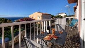 A balcony with a table set for a meal, a bottle of wine, and a chair. - Casa Margone - CALVI (CALVI)