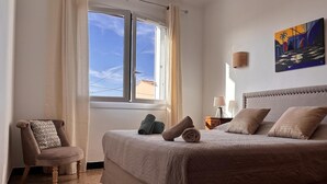 A hotel room with a bed, a chair, a nightstand, and a painting on the wall. - Casa Margone - CALVI (CALVI)