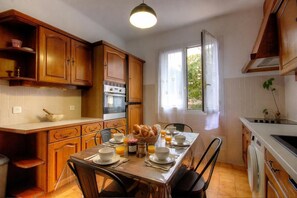 Eine Küche mit Holzausstattung, einem für das Frühstück gedeckten Esstisch und einem Fenster mit Vorhängen.