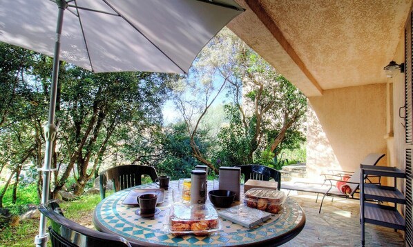 An outdoor dining area with a round table, chairs, and a large umbrella. - L'Olivo - LUMIO - Gîte (LUMIO)