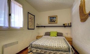 A bedroom with a bed, a window, a wall-mounted shelf, and a framed picture. - L'Olivo - LUMIO - Gîte (LUMIO)