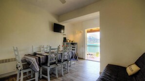 Un comedor con una mesa y sillas, un televisor montado en la pared y un balcón con vistas.