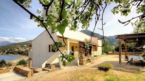 Una casa con base de piedra, fachada blanca y vista al mar.