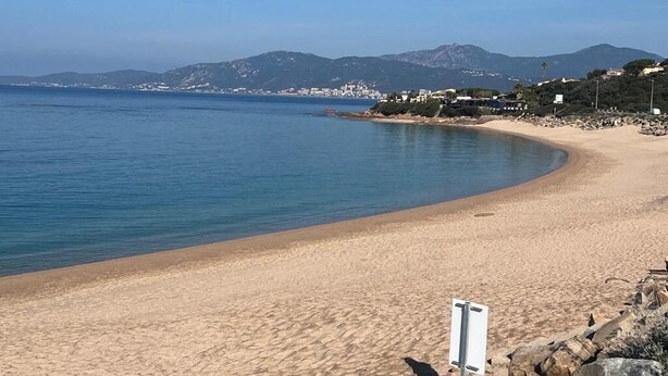 Ein Strand mit freiem Blick auf das Meer und entfernte Berge.
