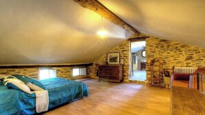 A cozy attic bedroom with a sloped ceiling, wooden beams, a bed with a blue cover, a dresser, and a mirror. - Casa Formosa - PENTA DI CASINCA (PENTA DI CASINCA)