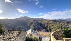 Un bâtiment dont le toit est fait de pierres, offrant une vue sur un paysage montagneux.