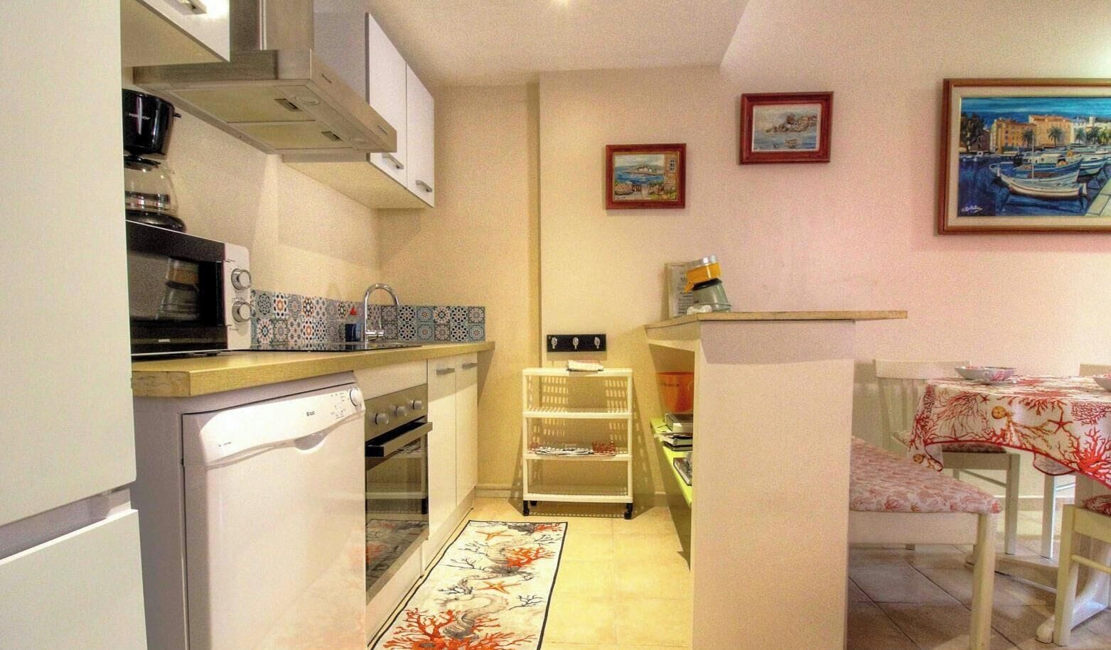 Une cuisine compacte équipée d’un four à micro-ondes, d’une cuisinière et d’un four. Elle comprend un coin repas avec une table et des chaises, ainsi qu’une petite étagère.