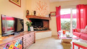 Ein Wohnzimmer mit Kamin, Fernseher, Sofa und Couchtisch.
